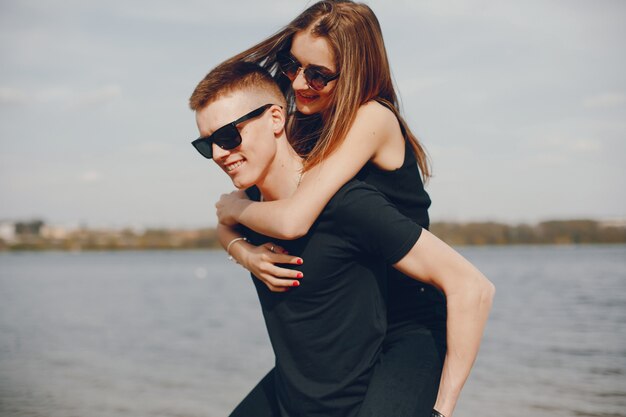 Un couple élégant et beau en vêtements noirs passe un bon moment sur la plage