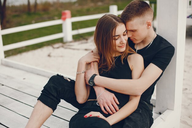 Un couple élégant et beau en vêtements noirs passe un bon moment sur la plage