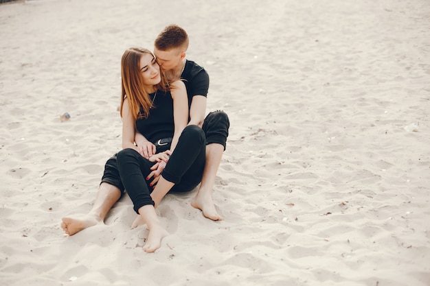 Un couple élégant et beau en vêtements noirs passe un bon moment sur la plage