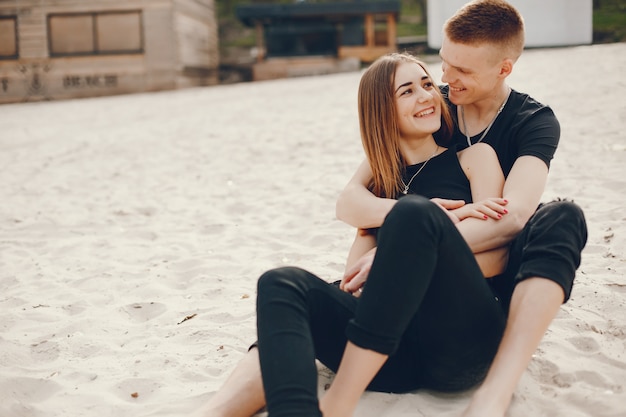 Un couple élégant et beau en vêtements noirs passe un bon moment sur la plage