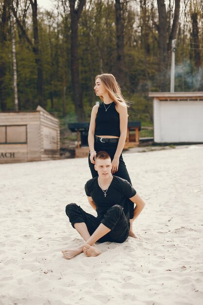Un couple élégant et beau en vêtements noirs passe un bon moment sur la plage