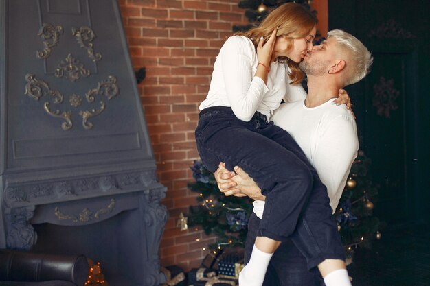 Couple élégant debout à la maison près de l'arbre de Noël