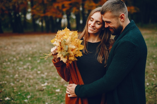 Couple élégant passe du temps dans un parc en automne