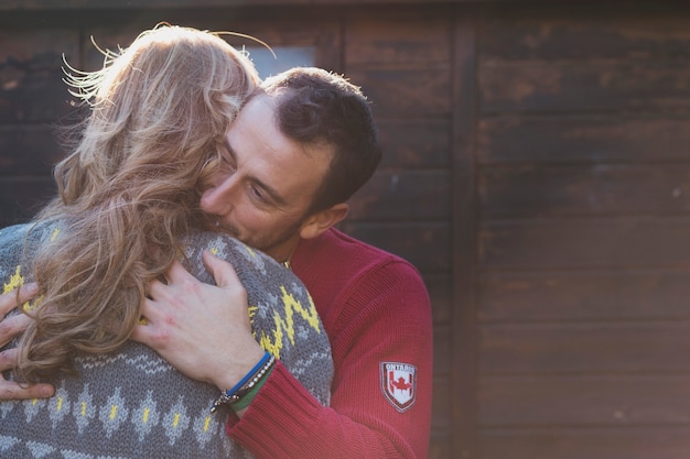 Photo gratuite couple embrassant au mur en bois