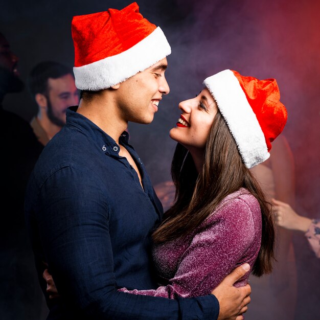 Couple embrassé portant des chapeaux de Noël