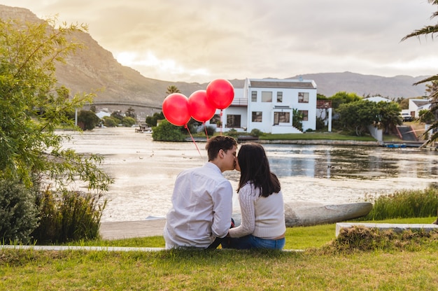 Photo gratuite couple embrasser dans un parc avec des ballons rouges