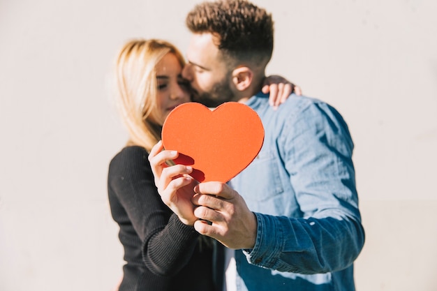 Couple énamouré posant avec coeur rouge