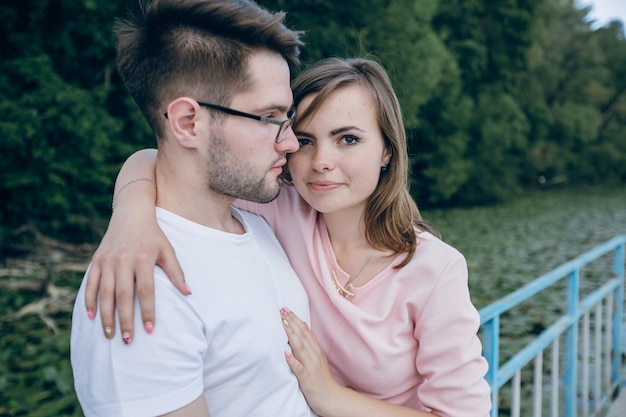 Couple enlacé appuyé sur une clôture bleue sur un pont