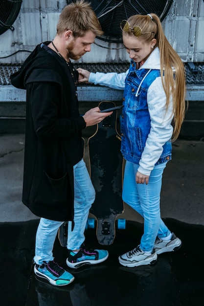 Couple ensemble à l'extérieur avec skateboard et smartphone