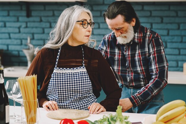 Couple européen senior mettant des tabliers dans la cuisine