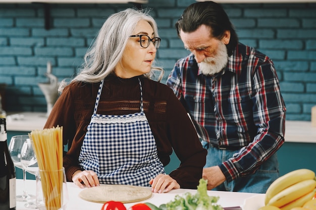 Couple européen senior mettant des tabliers dans la cuisine