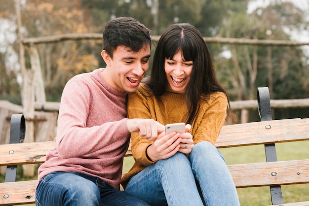 Couple excité en riant en regardant smartphone