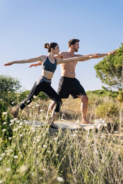 Photo gratuite couple faisant du yoga à la plage, herbe devant