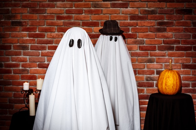 Couple de fantômes posant sur le mur de briques. Fête d'Halloween.