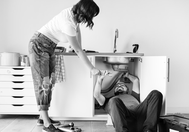 Couple fixant un évier de cuisine