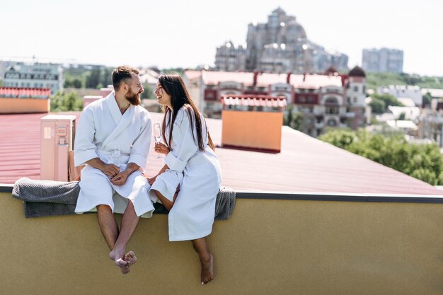 Couple flirter avec du vin mousseux sur un toit