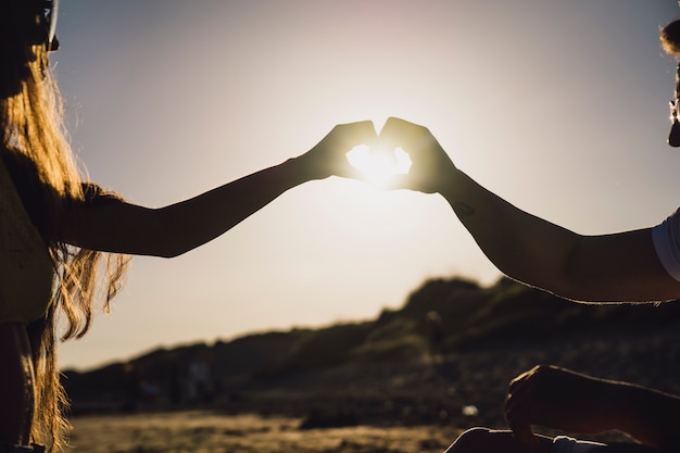 Photo gratuite couple formant coeur avec les mains