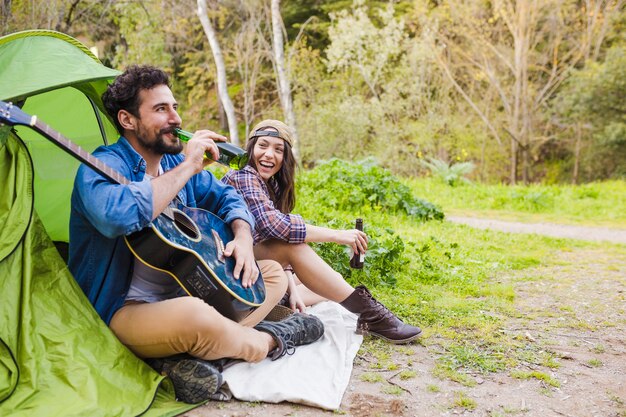 Couple gai avec guitare, boire de la bière