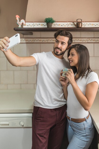 Couple gai posant pour selfie en cuisine
