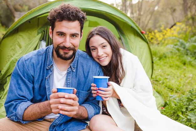 Couple gai avec des tasses près de la tente
