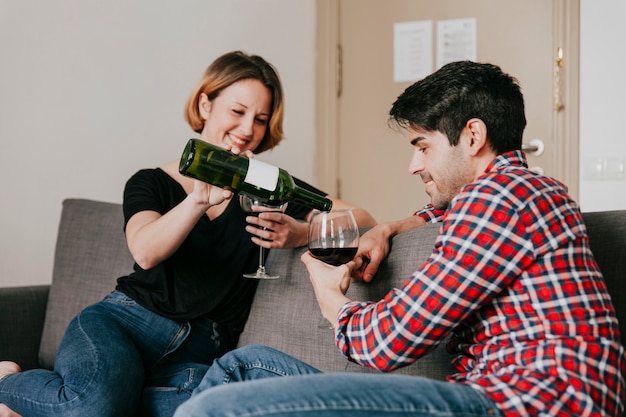 Photo gratuite couple gai, verser le vin à la maison