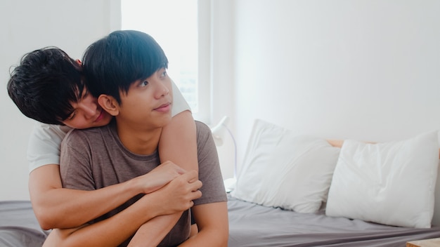 Couple gay asiatique s'embrasser sur un lit à la maison. Les jeunes hommes asiatiques LGBTQ + heureux se détendre se reposer ensemble passent un moment romantique après le réveil dans la chambre à la maison le matin.