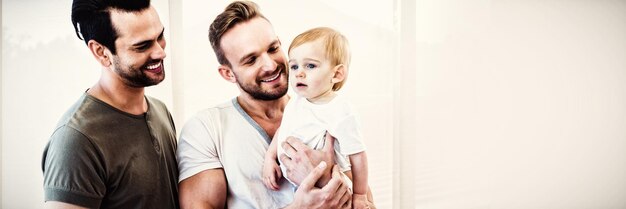 Couple gay souriant avec enfant à la maison
