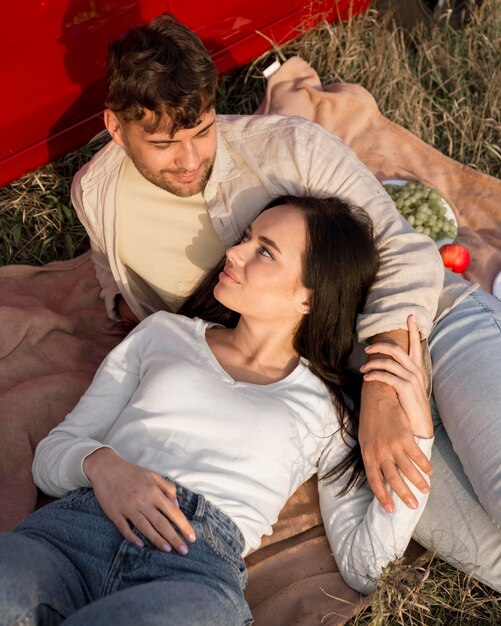 Couple grand angle portant sur l'herbe