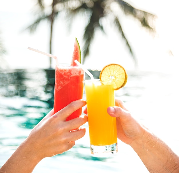 Couple grillé avec des cocktails au bord de la piscine