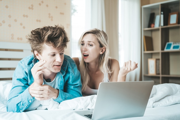 Couple heureux à l&#39;aide d&#39;un ordinateur portable sur le lit