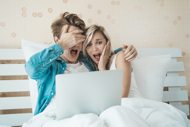 Couple heureux à l&#39;aide d&#39;un ordinateur portable sur le lit