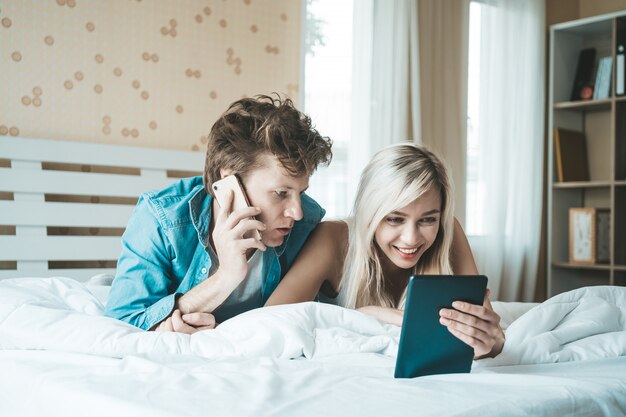 Couple heureux à l&#39;aide d&#39;une tablette sur le lit