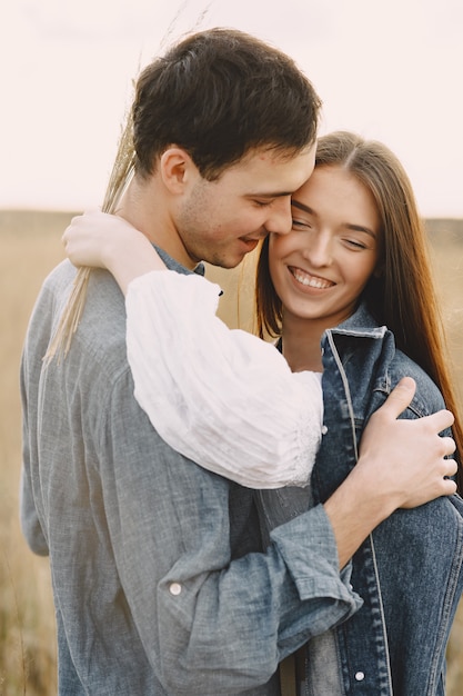 Couple heureux en amour dans le champ de blé au coucher du soleil