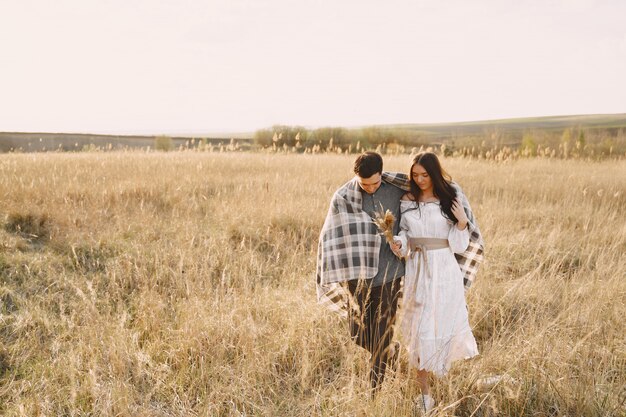 Couple heureux en amour dans le champ de blé au coucher du soleil