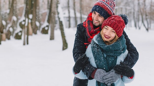 Couple heureux amoureux embrassant dans la neige