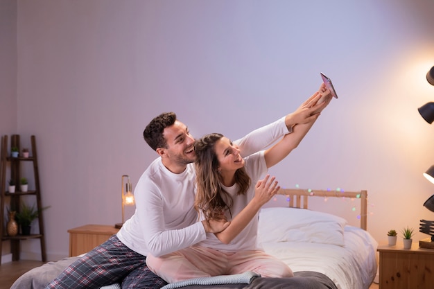 Couple heureux au lit prenant selfie