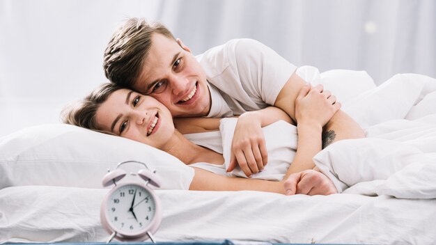 Couple heureux au lit près de l&#39;horloge