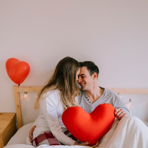 Photo gratuite couple heureux avec coeur sur le lit