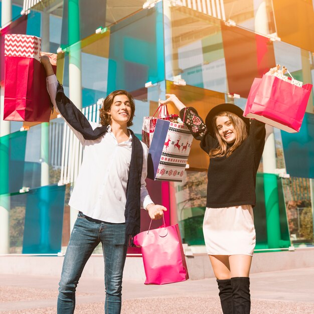 Photo gratuite couple heureux debout avec des sacs shopping vives