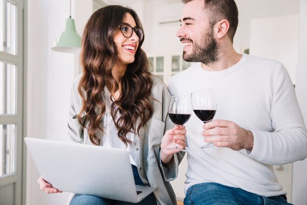 Couple heureux avec du vin et un ordinateur portable