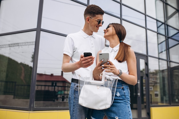 Couple heureux ensemble dans la ville à l'aide de téléphone