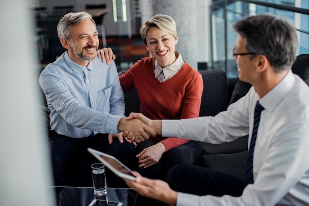 Photo gratuite un couple heureux est parvenu à un accord avec leur agent d'assurance au bureau