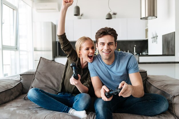 Couple heureux, jouer jeux vidéo, et, regarder appareil-photo