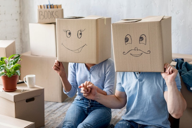 Photo gratuite couple heureux à la maison le jour du déménagement avec des boîtes au-dessus des têtes