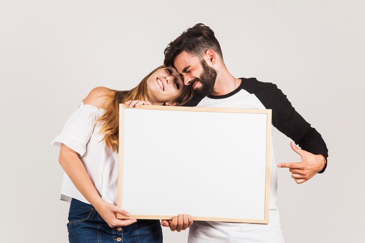 Photo gratuit couple heureux montrant un tableau blanc