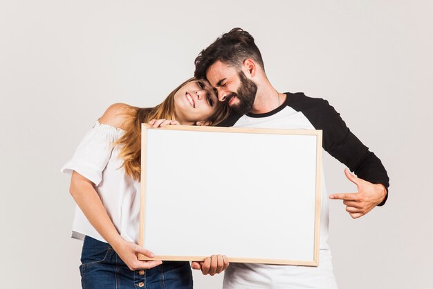 Couple heureux montrant un tableau blanc