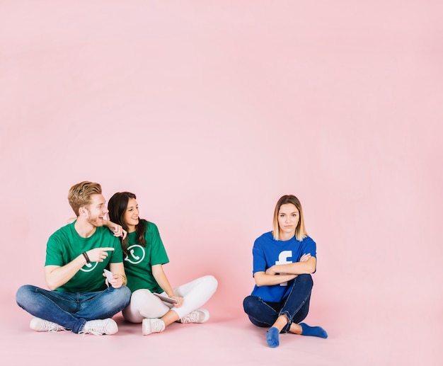 Couple heureux en regardant une femme triste sur fond rose