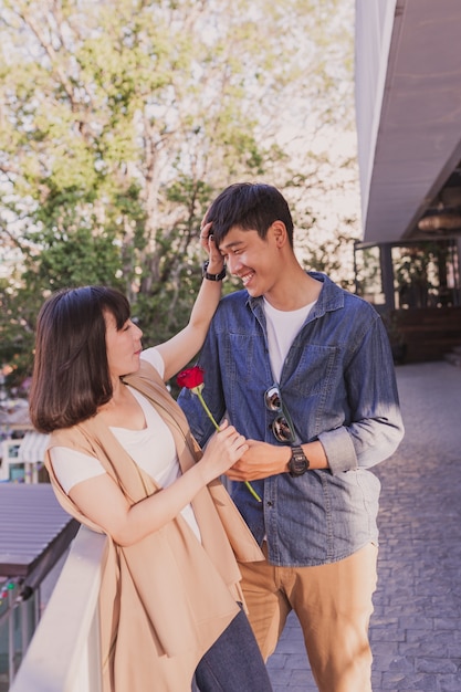 Photo gratuite couple heureux avec une rose se penchant sur une balustrade