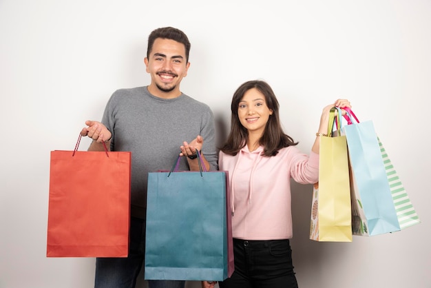 Couple heureux avec des sacs à provisions debout sur blanc.