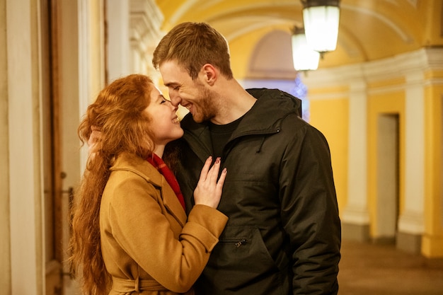 Un couple heureux se tient dans une étreinte dans la rue le soir dans les lumières de fête